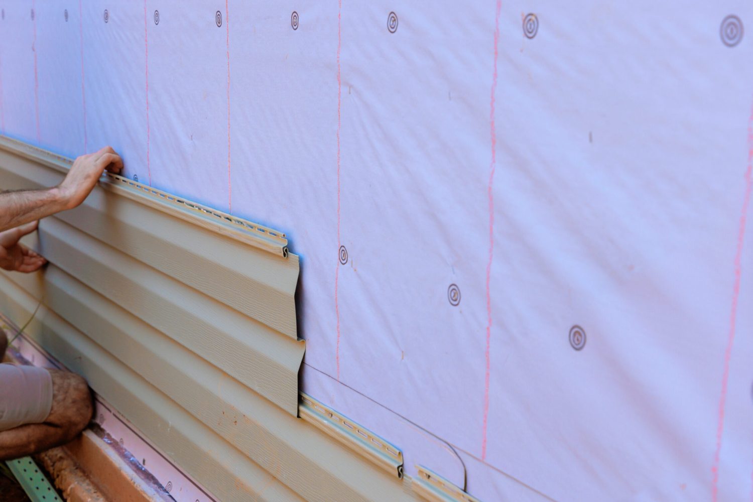 In process of installing vinyl siding on new home facade, handyman installs vinyl PVC siding